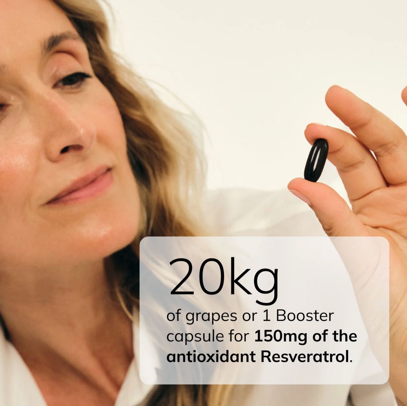 Woman holding a single Age Shield NAD+ Booster softgel capsule containing 150mg of resveratrol